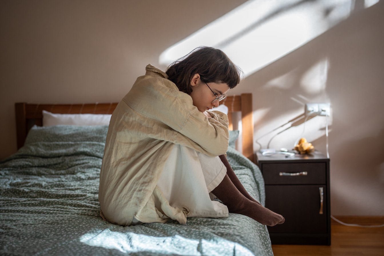 Apathetical Teen Girl Sitting on Bed Embracing Knees Feeling Procrastination, Depression, Loneliness