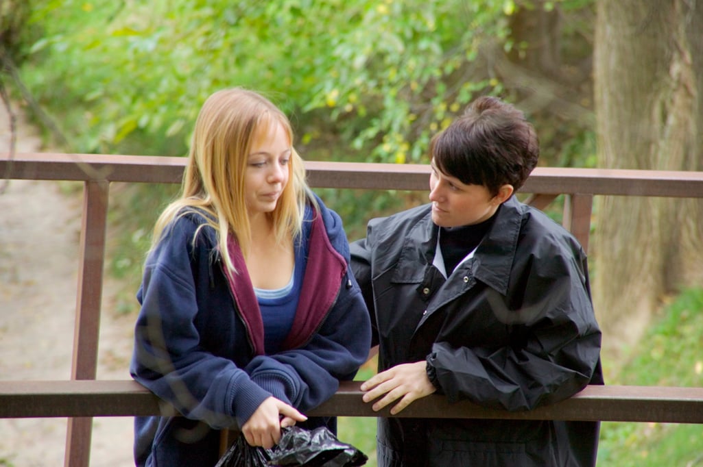 Social worker talking to homeless teen girl on bridge